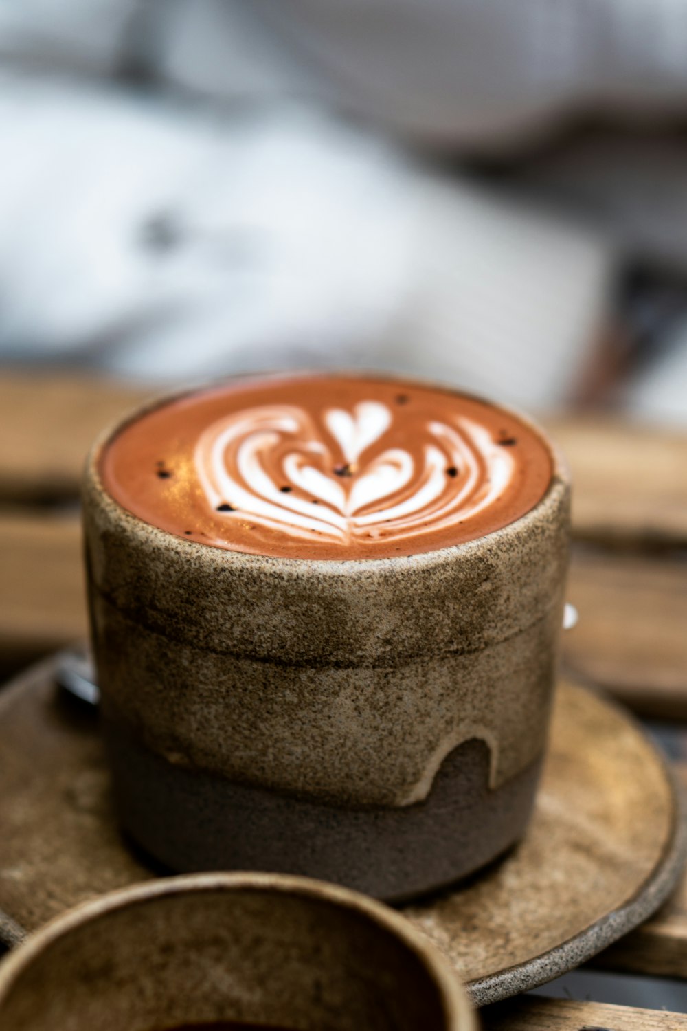 a cappuccino on a plate with a cup of coffee