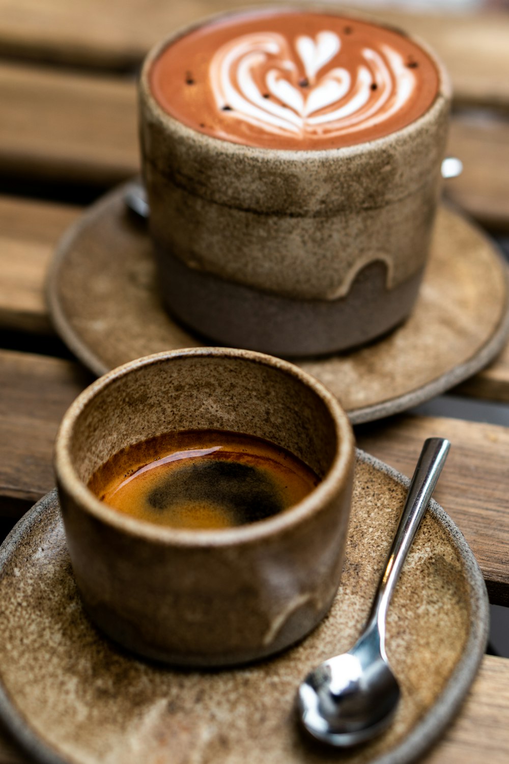 a cup of coffee and a spoon on a wooden table