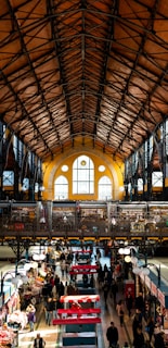 Sunlight filtering through the intricate arches of the Great Market Hall bustling with visitors.
