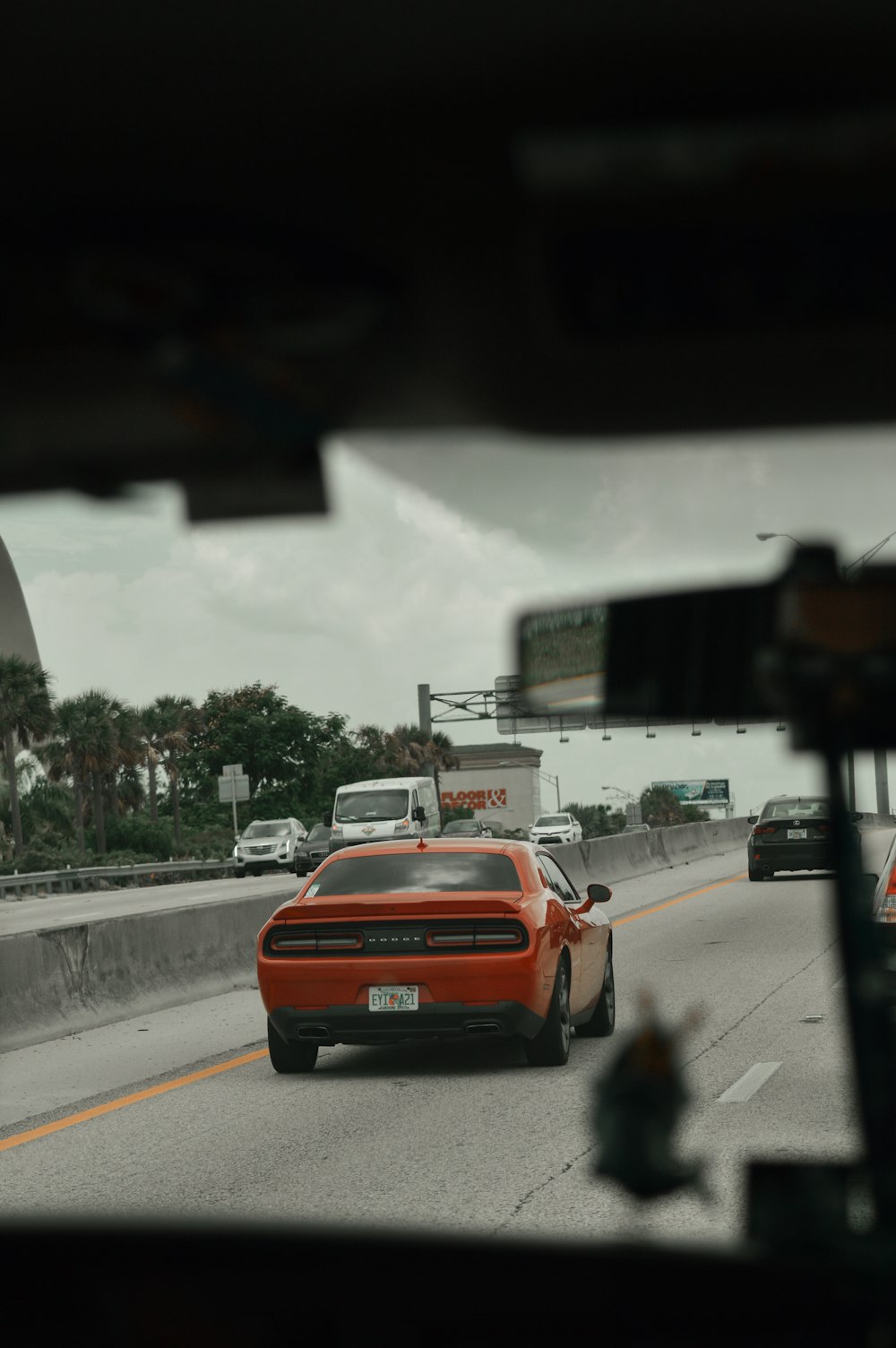 a red car driving down a highway next to a bridge