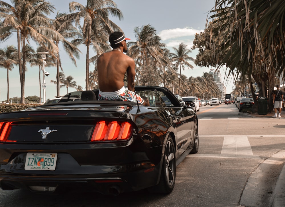 a man riding on the back of a black car