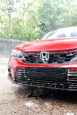 a red car is parked in the rain