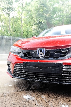 a red car is parked in the rain
