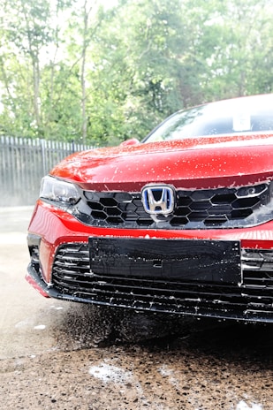 a red car is parked in the rain