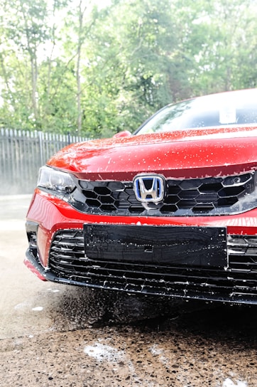 a red car is parked in the rain