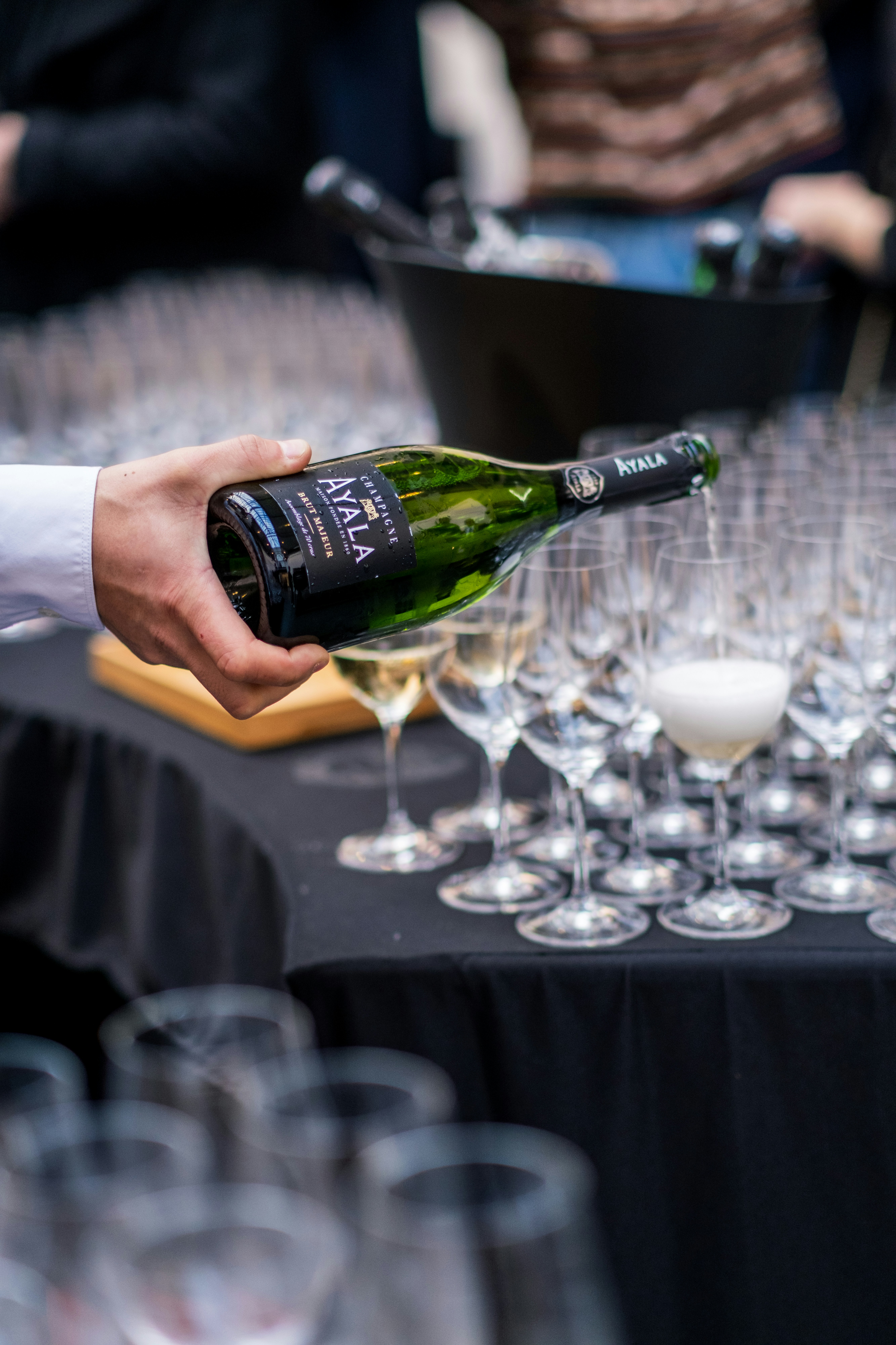 a person pouring a bottle of wine into wine glasses