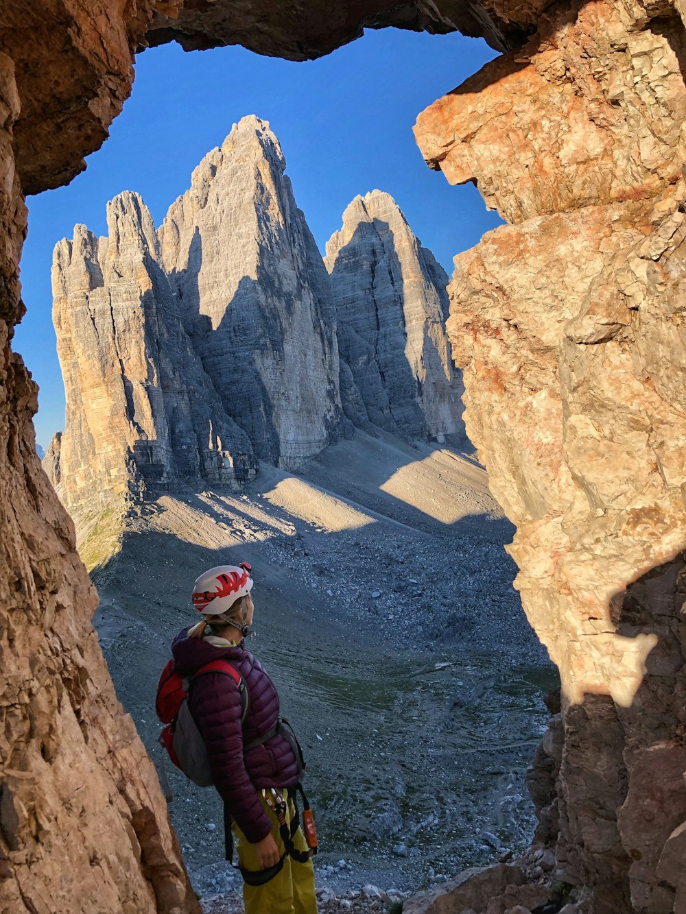 a person standing in a cave looking at mountains