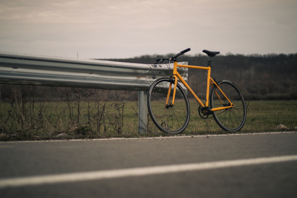a yellow bike parked next to a metal fence