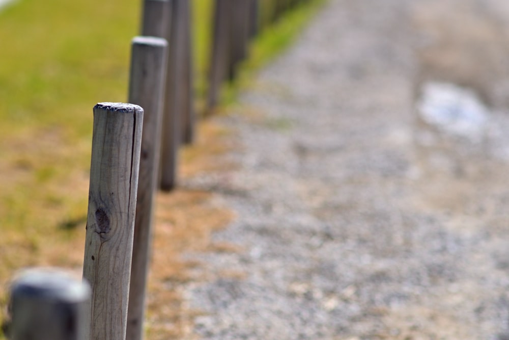 a close up of a wooden fence on a gravel road