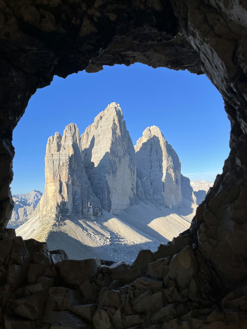 a view of a mountain range through a hole in a rock wall