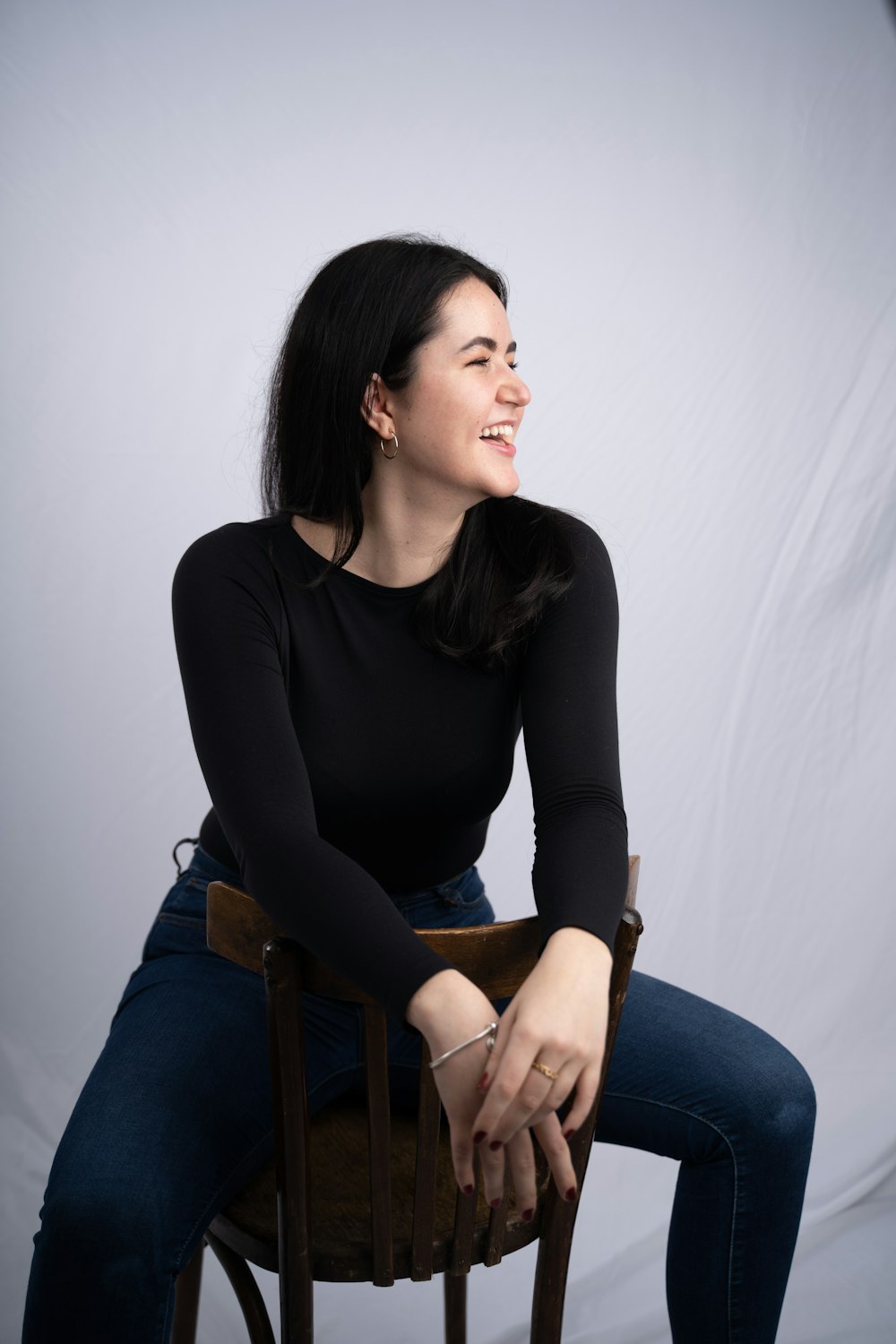 a woman sitting on top of a wooden chair