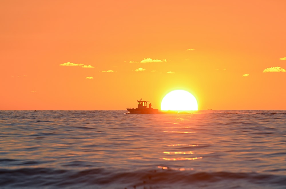 a small boat in the middle of the ocean at sunset