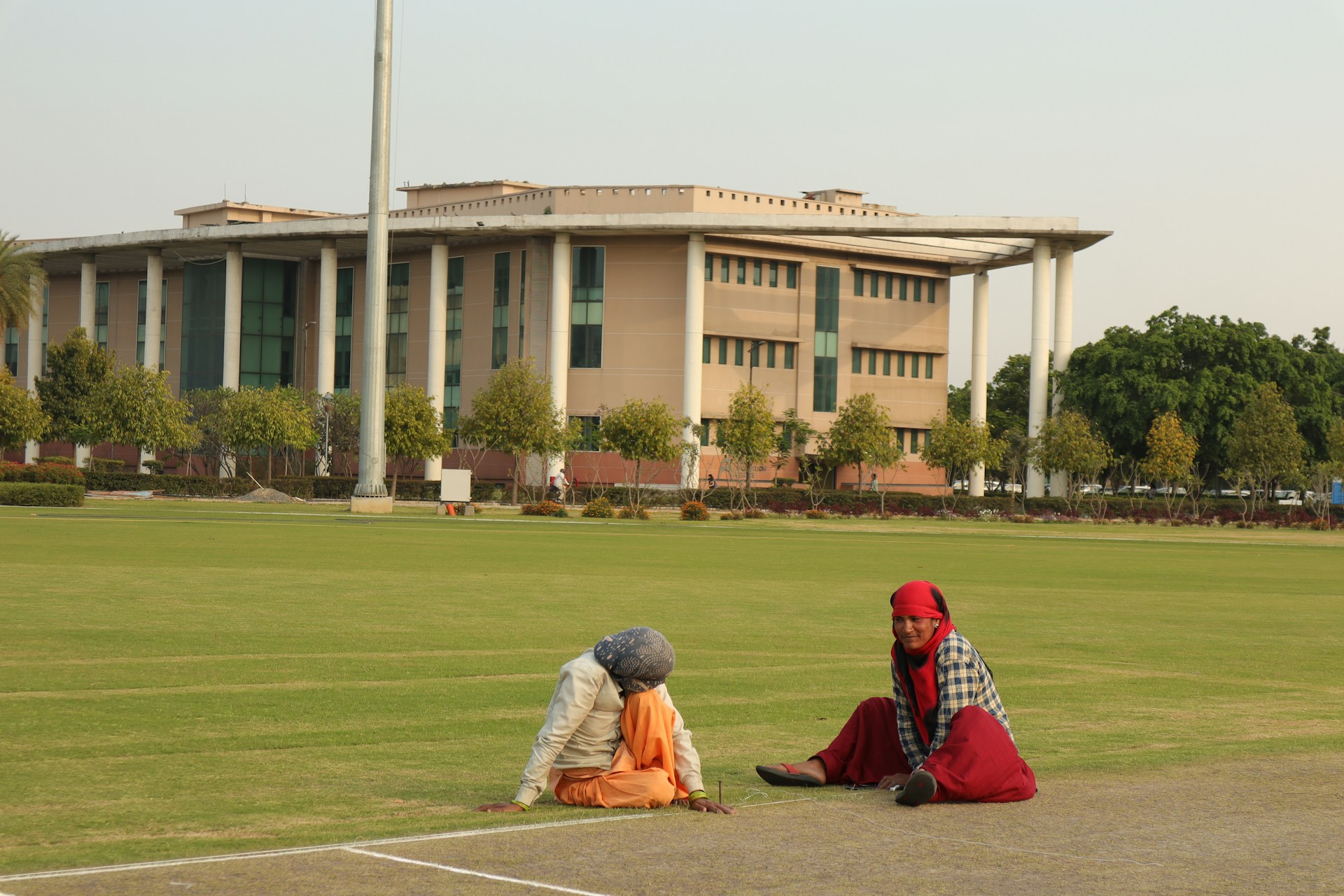 two people sitting on the ground in front of a building