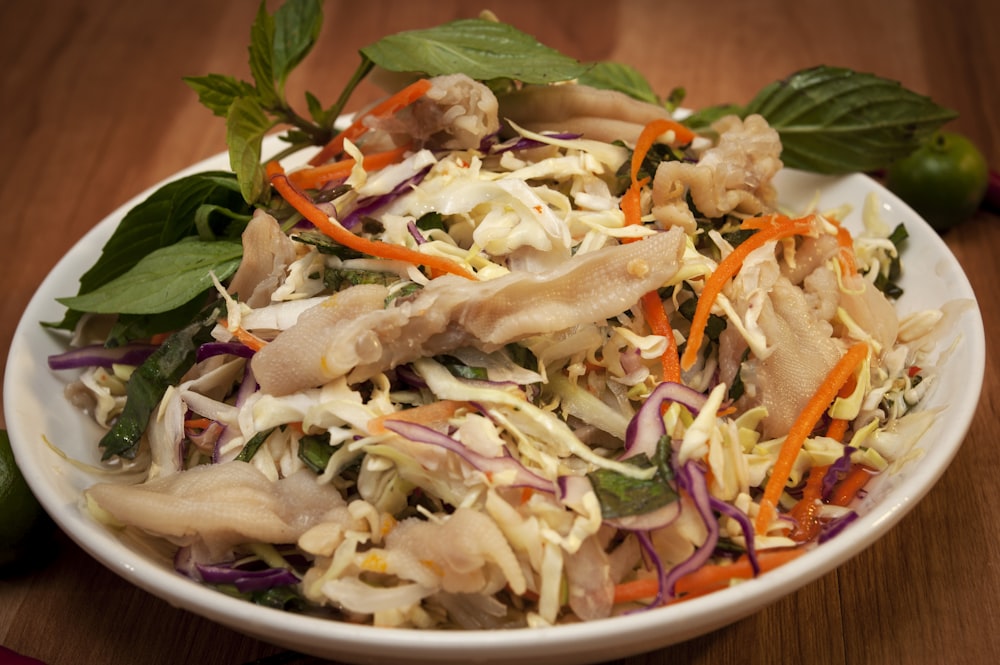 a white bowl filled with a salad on top of a wooden table