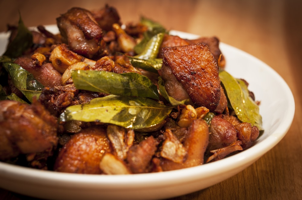 a white bowl filled with meat and vegetables