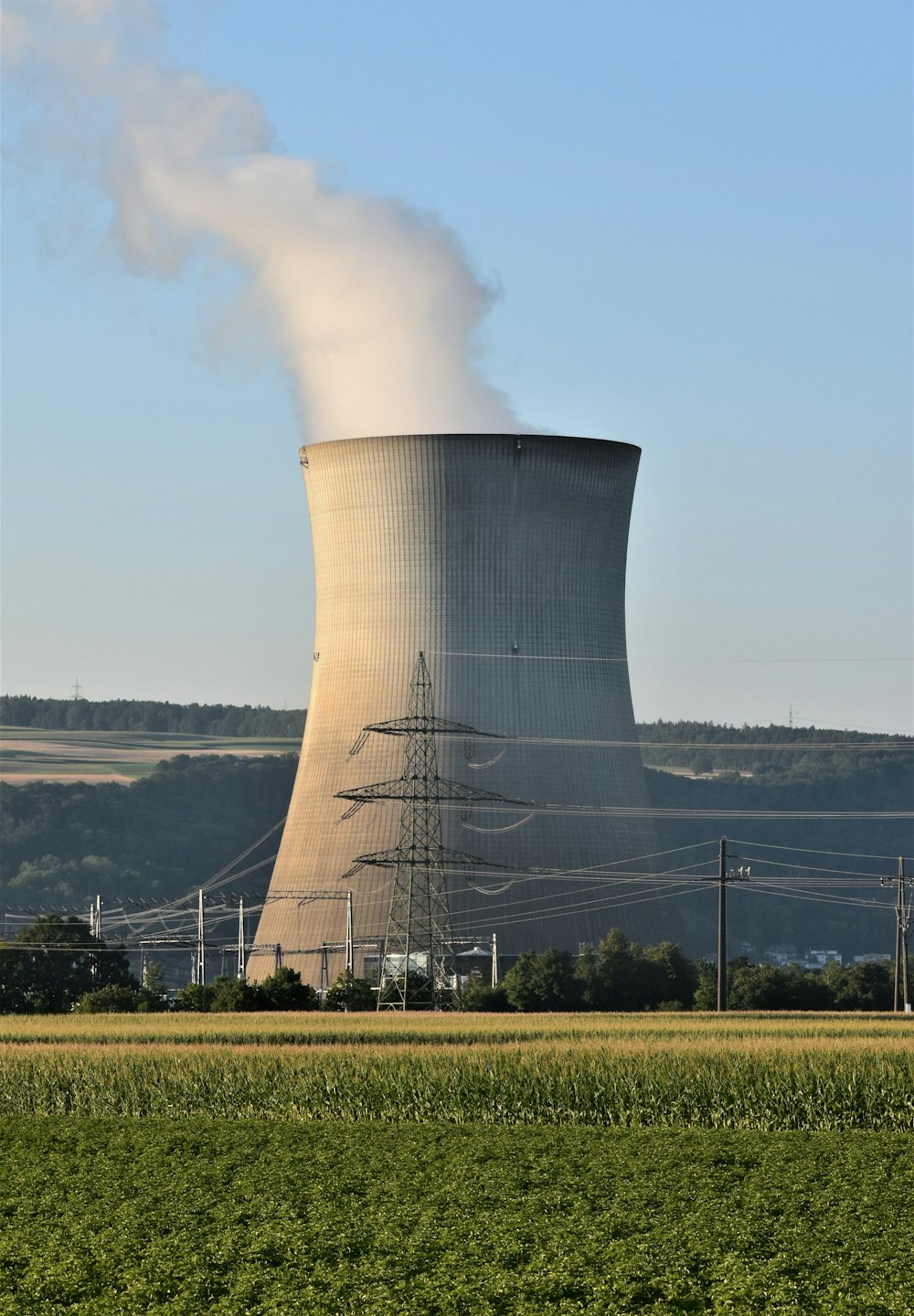 a power plant emits smoke as it sits in the middle of a field