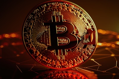 A large, close-up view of a Bitcoin coin with intricate circuit-like patterns on its surface. The background is a dark, abstract representation of a digital network with glowing orange and yellow lights.