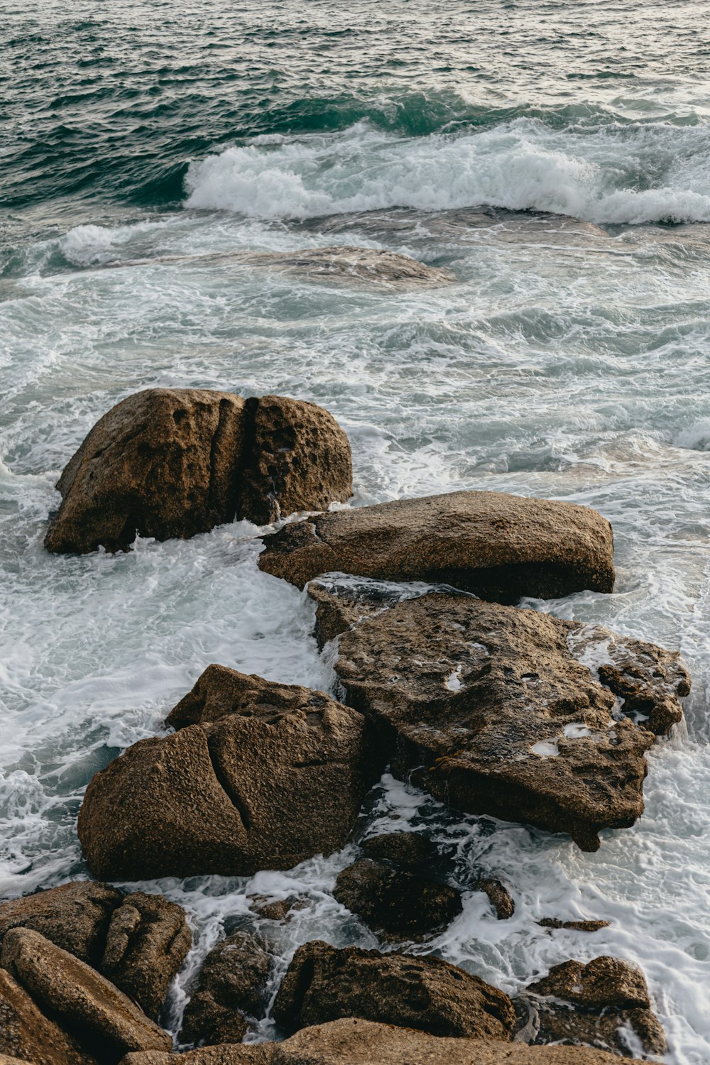 a person standing on top of a rock next to the ocean