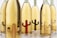 A collection of glass bottles filled with a golden liquid is arranged closely together. Each bottle features an embossed motif of a cactus shape in varying colors such as brown and red, which adds a unique design element. The bottles are labeled with 'Porfidio' and have a green label on top.