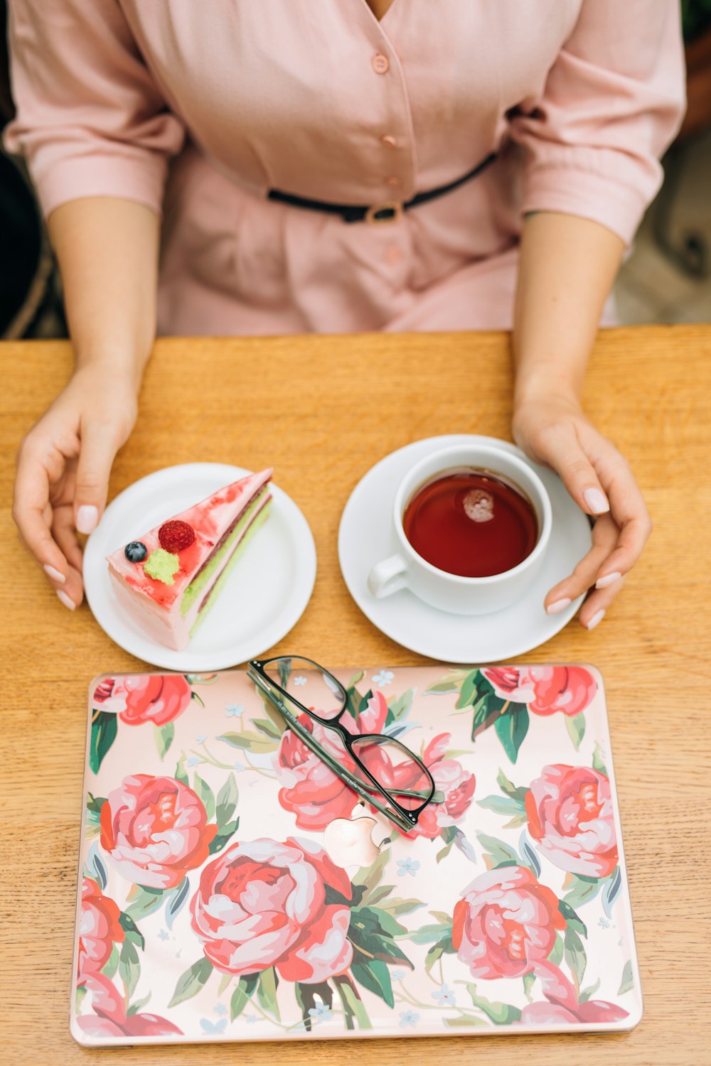 a woman sitting at a table with a piece of cake and a cup of tea