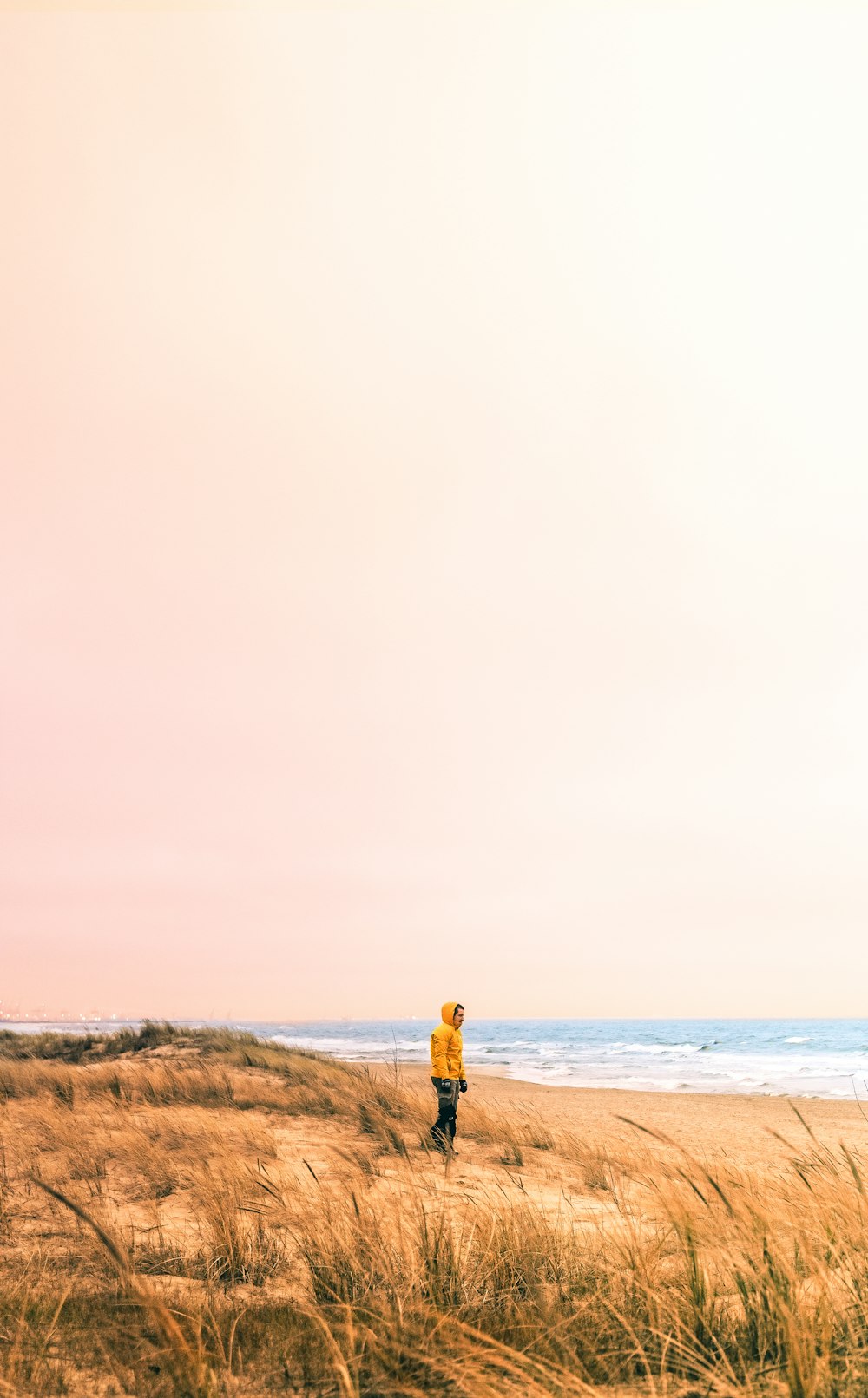 a person in a yellow jacket standing on a beach