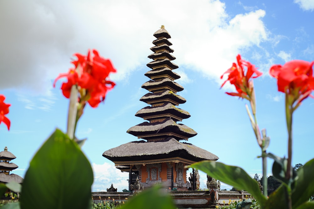 a tall tower with red flowers in front of it