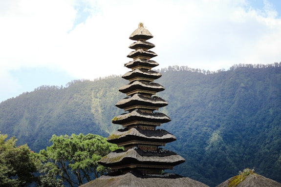 a tall tower made of rocks sitting on top of a lush green hillside
