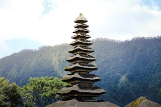 a tall tower made of rocks sitting on top of a lush green hillside