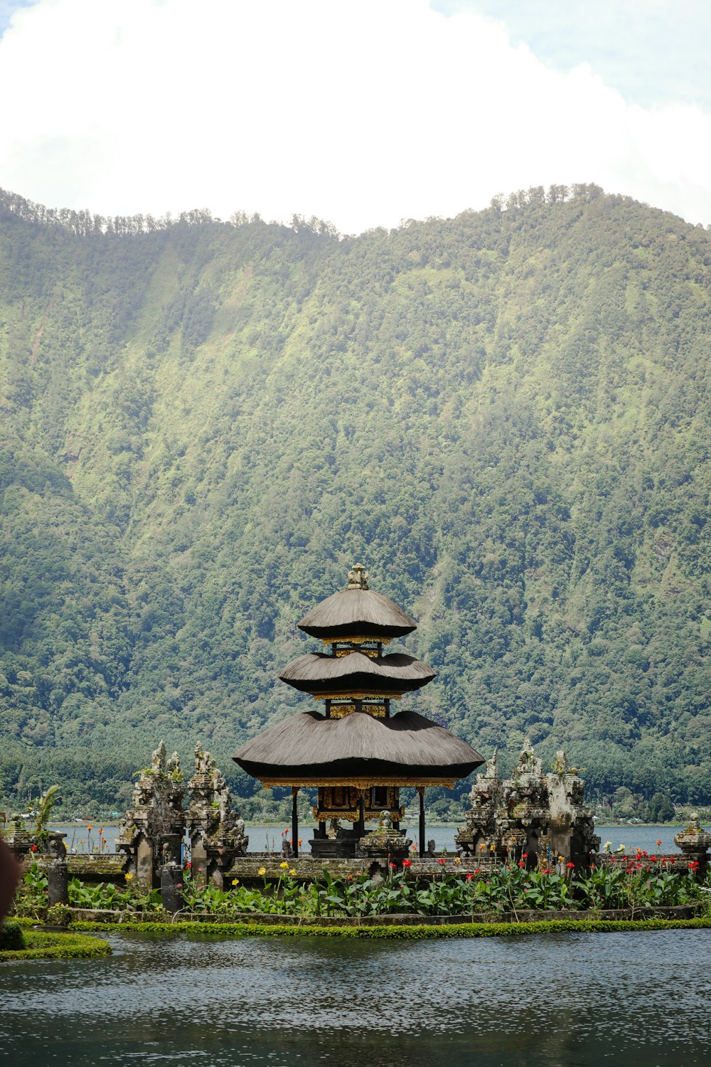 a pagoda in the middle of a lake with a mountain in the background