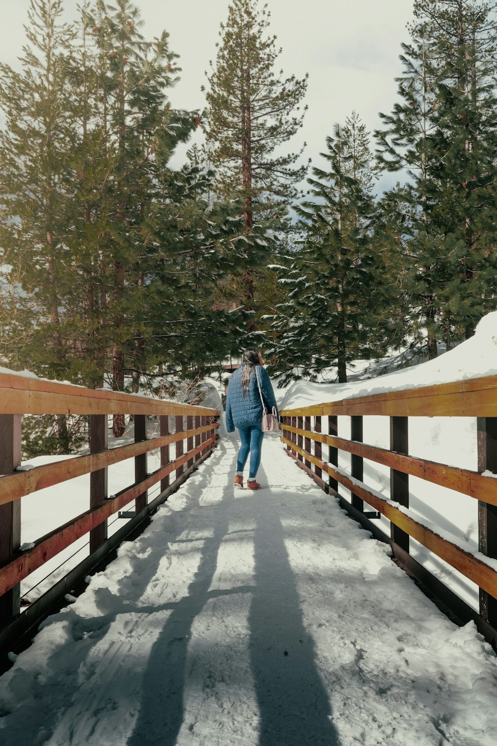 a person walking across a snow covered bridge