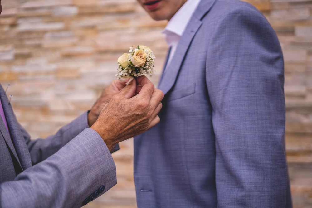 a man in a gray suit is holding a boutonniere