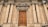 An ornate, large wooden door is set within a grand architectural facade featuring tall columns and intricate stone carvings. The structure appears to be historic, with classical design elements including symmetry, decorative moldings, and a sculpted emblem above the entrance.