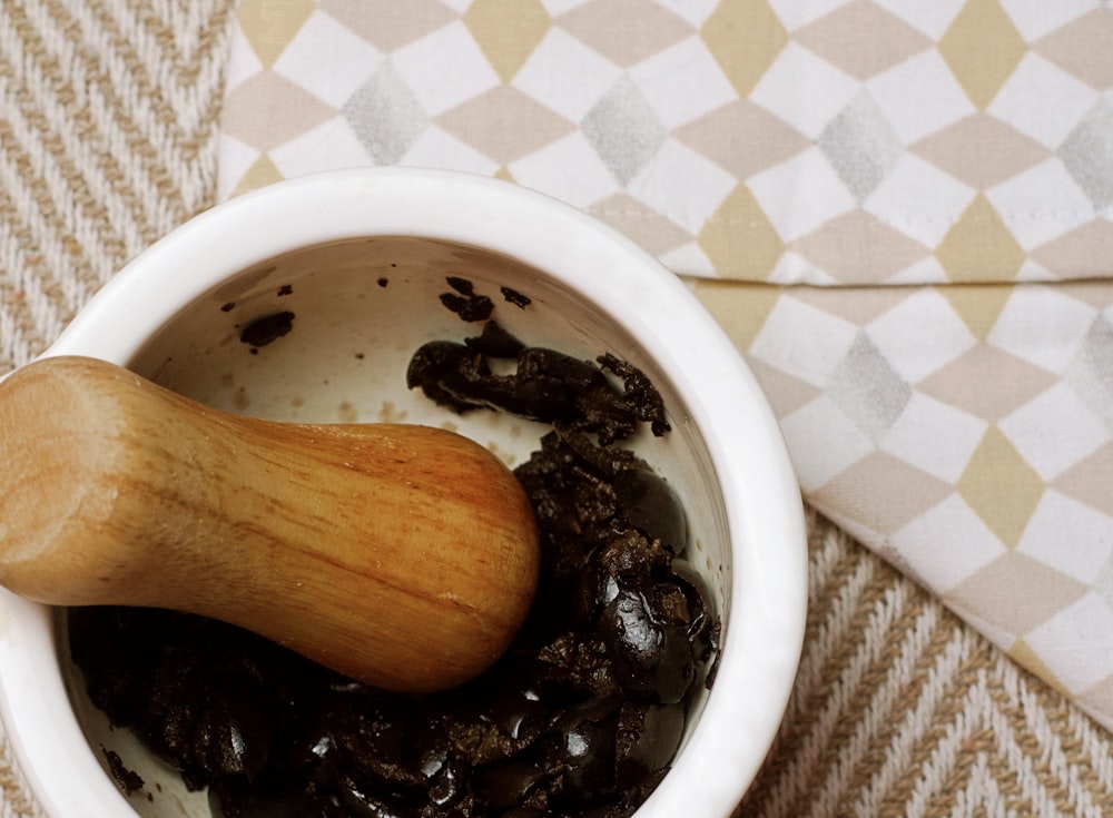 a wooden spoon in a white bowl filled with raisins