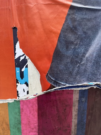 A bright collage featuring torn paper and fabric pieces arranged in a whimsical pattern.