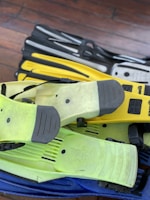A collection of snorkeling masks and fins neatly arranged on a wooden table under natural light