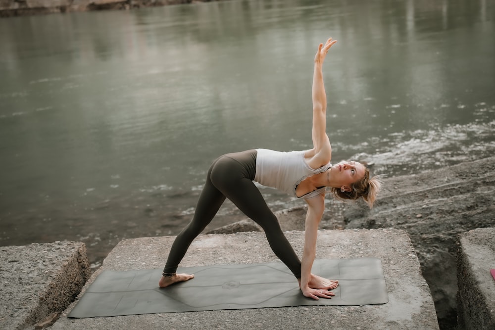 Eine Frau, die eine Yoga-Pose an einem Fluss macht