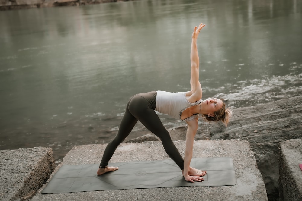 uma mulher que faz uma pose de yoga à beira de um rio