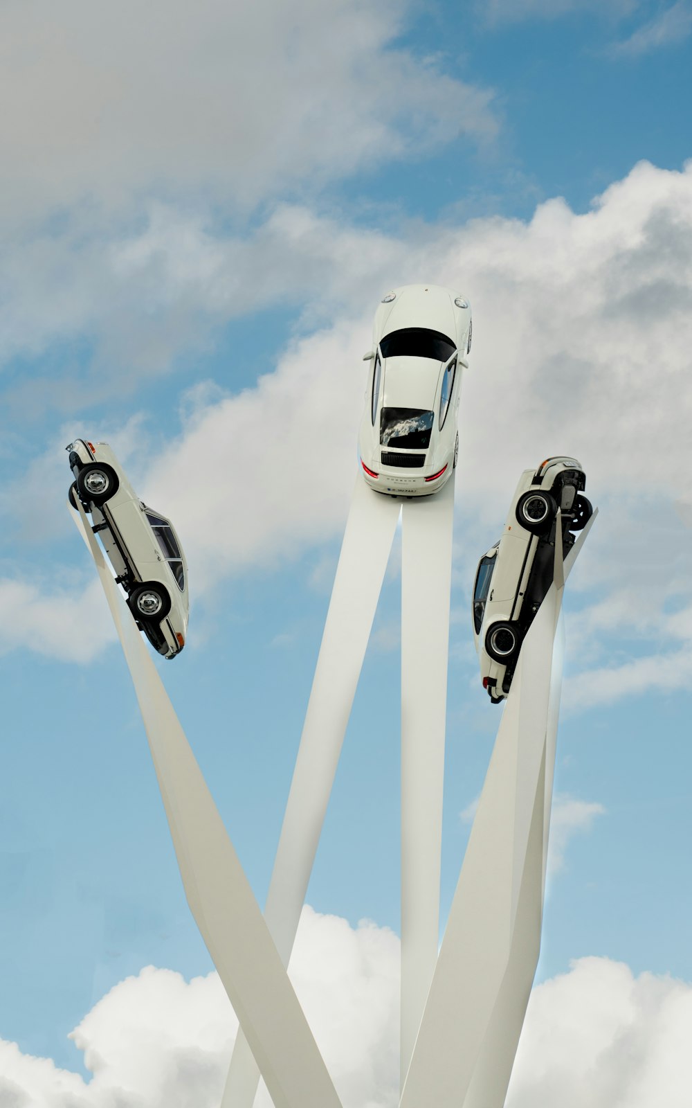 three cars are parked in the middle of a sculpture