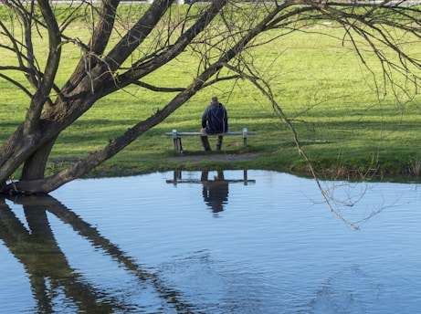 A young man sitting peacefully on a park bench, surrounded by nature, reflecting calm and mental clarity.