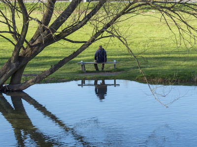 A peaceful outdoor scene with a person sitting quietly on a bench, reflecting.
