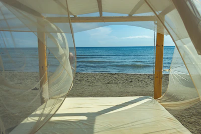 A serene beach house porch with soft linen curtains gently swaying in the ocean breeze.