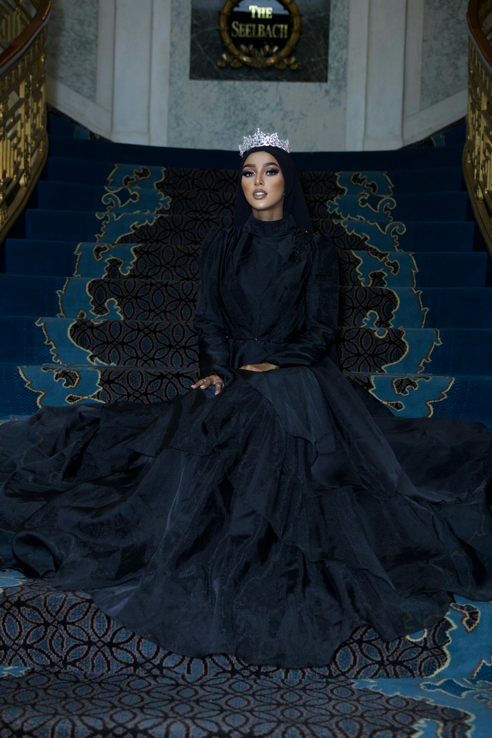 a woman in a black dress sitting on a blue staircase