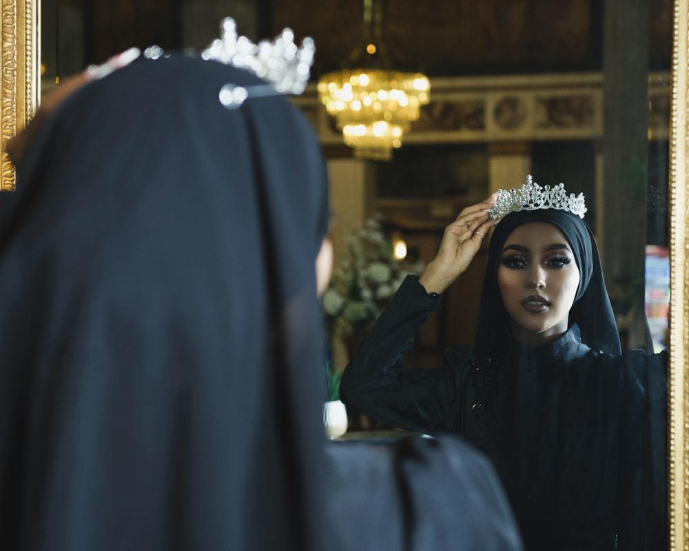 a woman wearing a tiara looking in a mirror