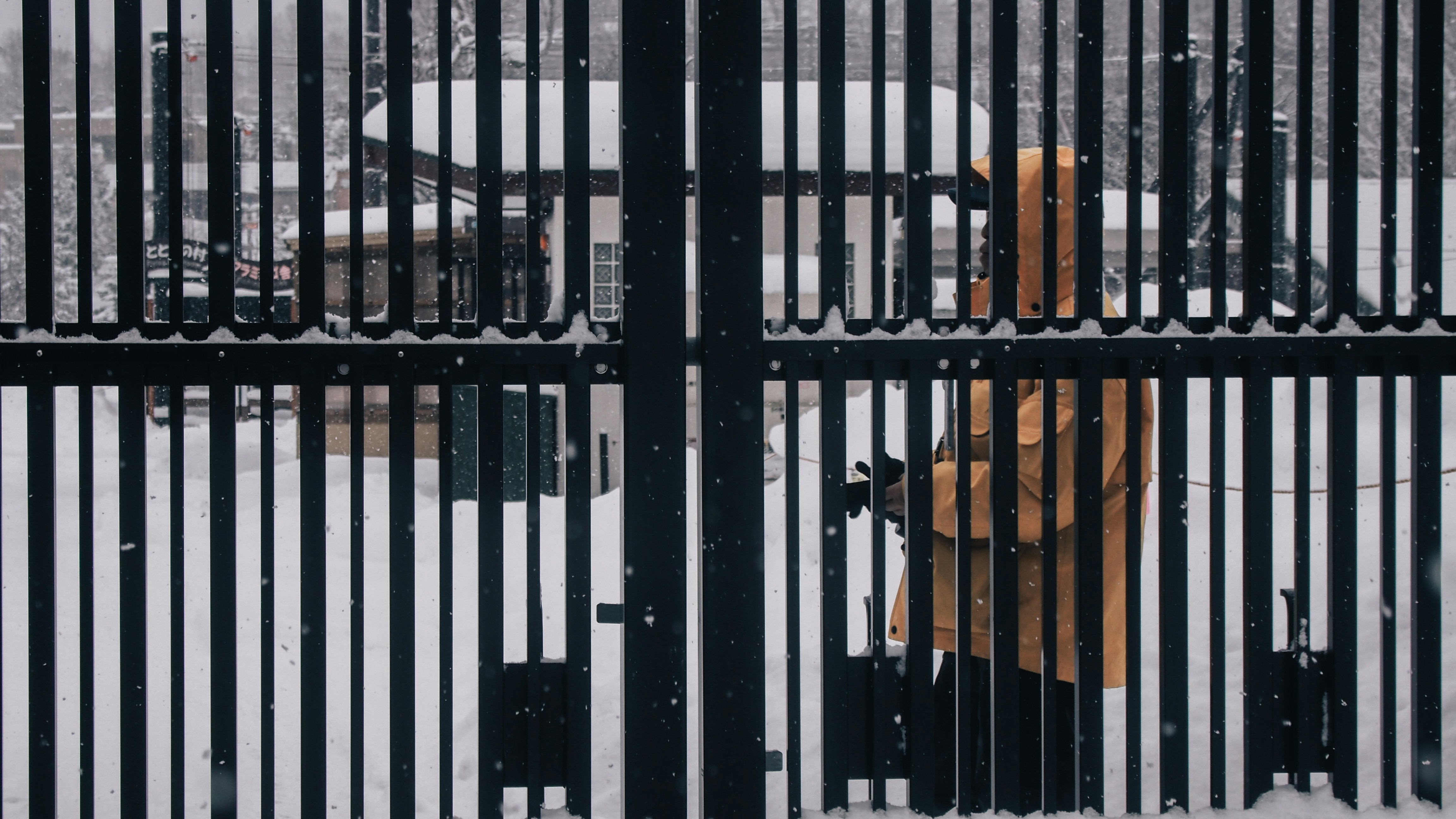 a yellow fire hydrant behind a black fence