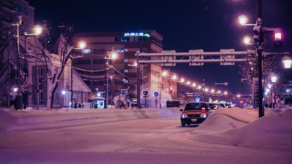 a car driving down a snow covered street at night