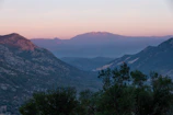 A serene sunset over the lush green valleys of Neelum Valley with distant mountain peaks.