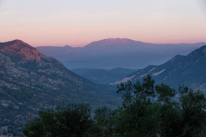 A serene sunset over the lush green valleys of Neelum Valley with distant mountain peaks.