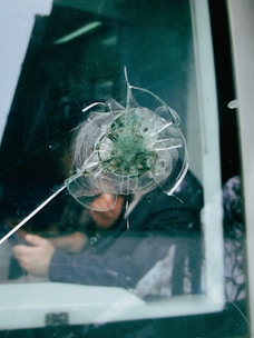 a man looking through a broken glass window
