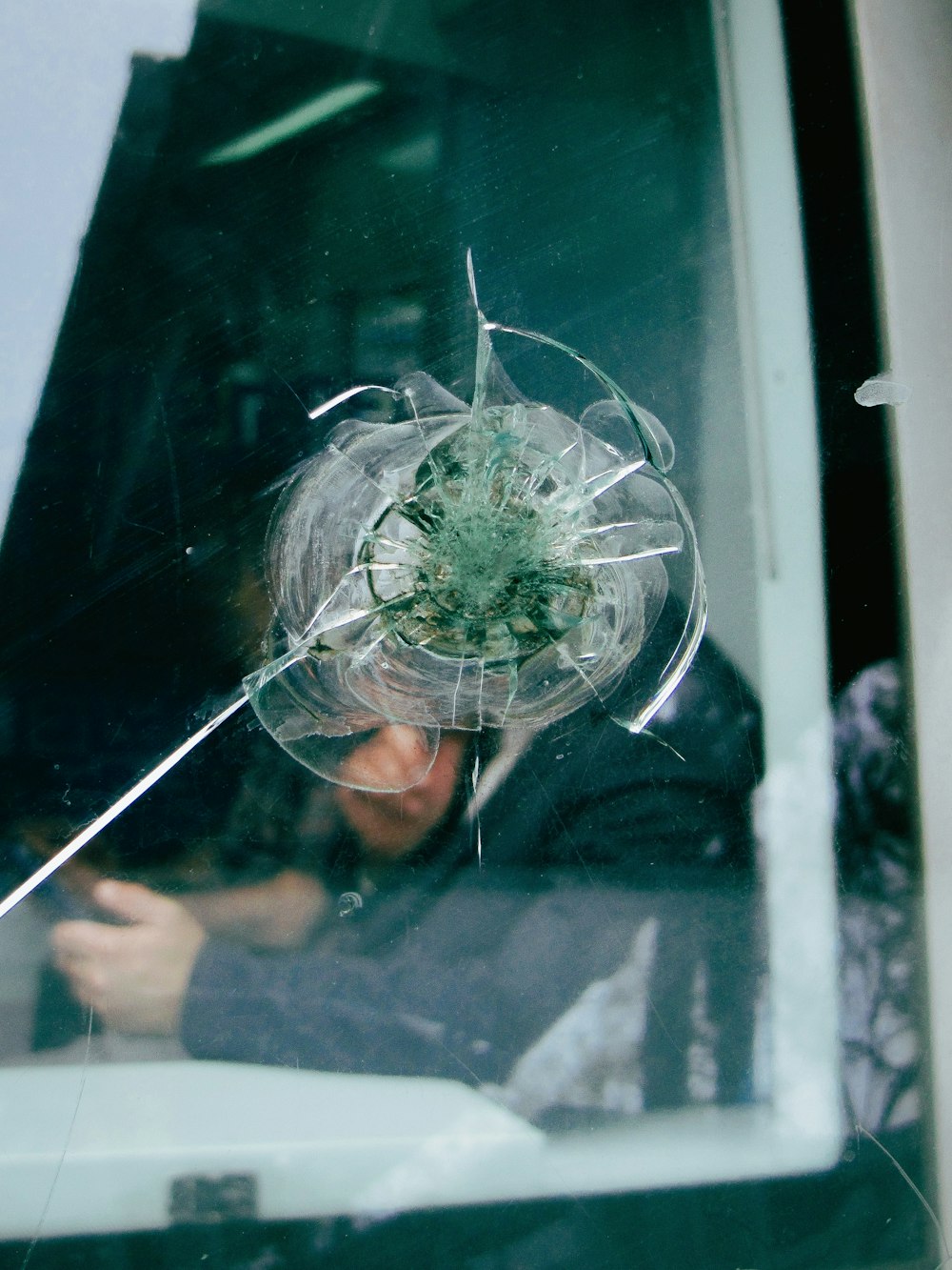 a man looking through a broken glass window