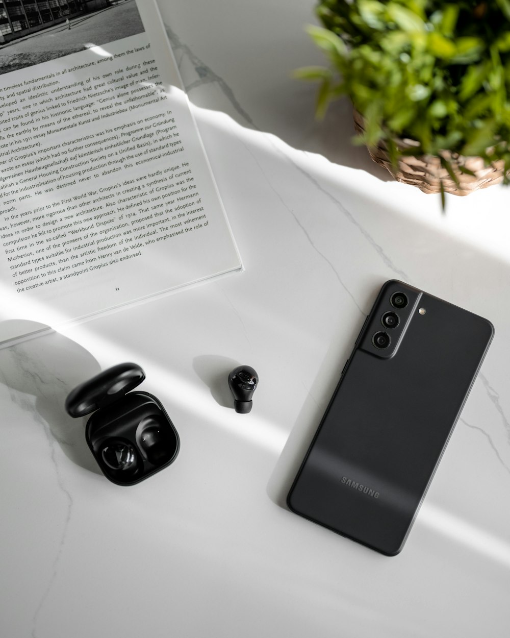 a black cell phone sitting on top of a table next to a plant